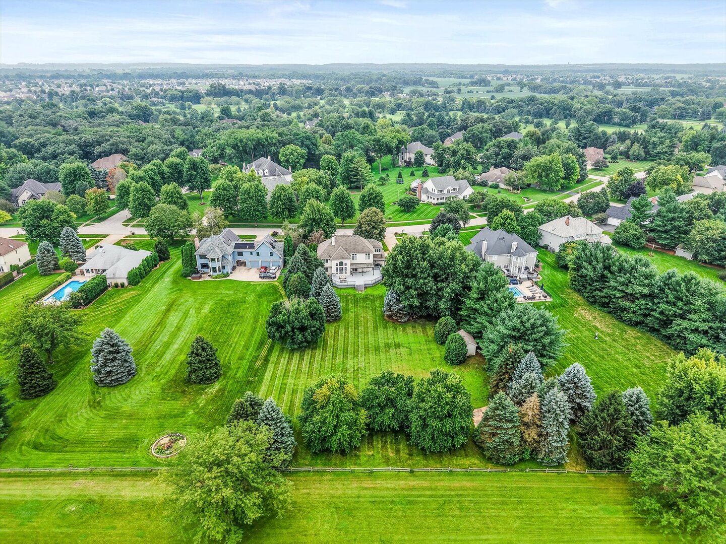 Aerial view of the property’s expansive lawn, mature trees, and neighboring homes.