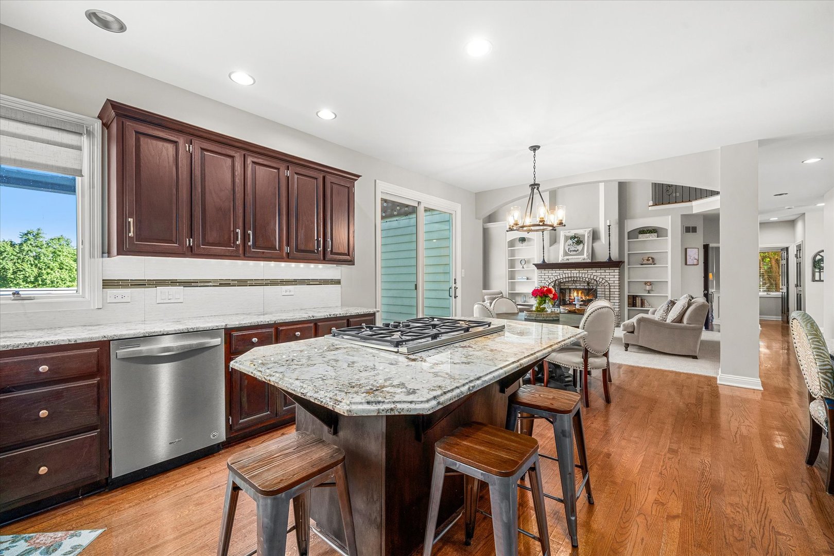 Kitchen with cherry cabinets, granite cooktop island, and an open view to the fireplace living room.