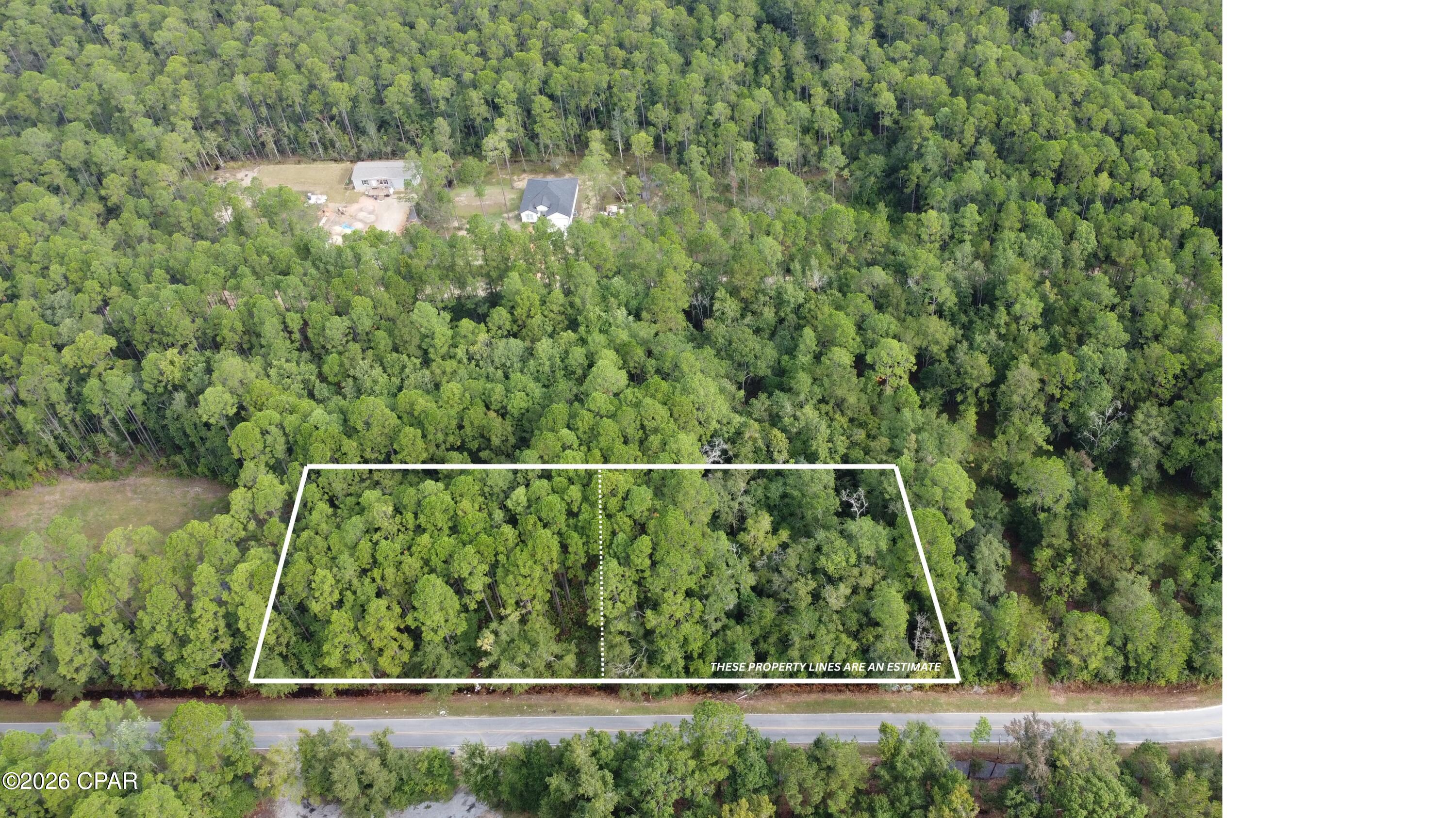 Aerial view of a wooded roadside parcel with estimated boundaries outlined in white.