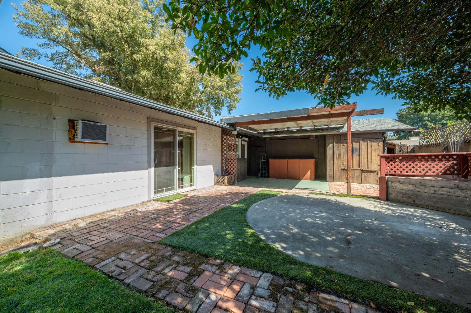 Backyard patio with a brick walkway, sliding glass door, and covered outdoor area.