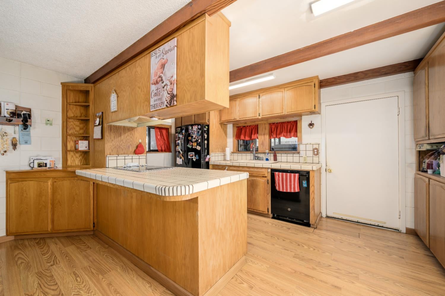 Kitchen with a large tiled island, honey-colored wood cabinetry, and exposed ceiling beams.