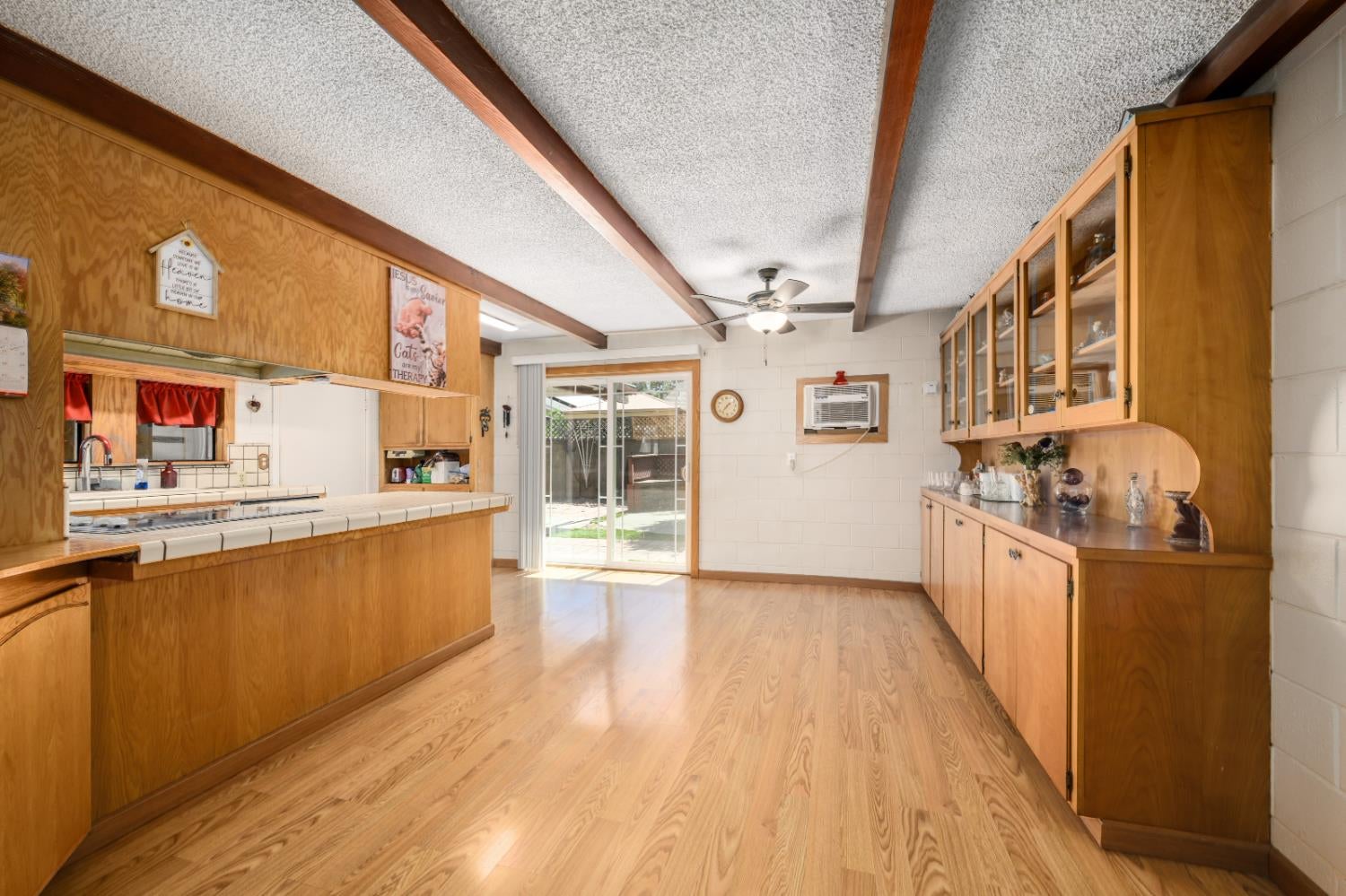 Kitchen with honey-colored wood cabinetry, a tiled breakfast counter, and sliding glass doors to the yard.