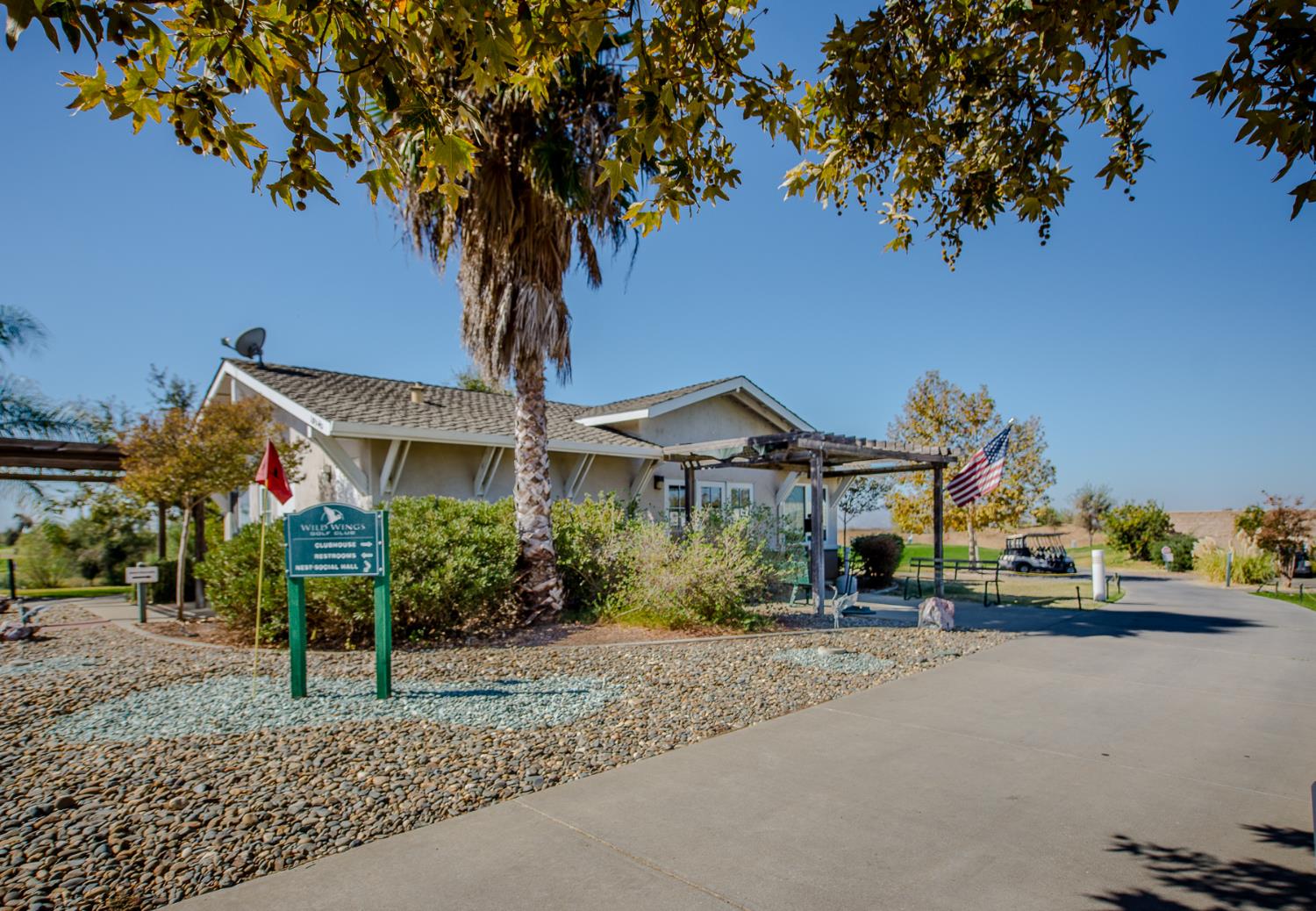 Community clubhouse with a pergola, Wild Wings sign, American flag, and golf cart.