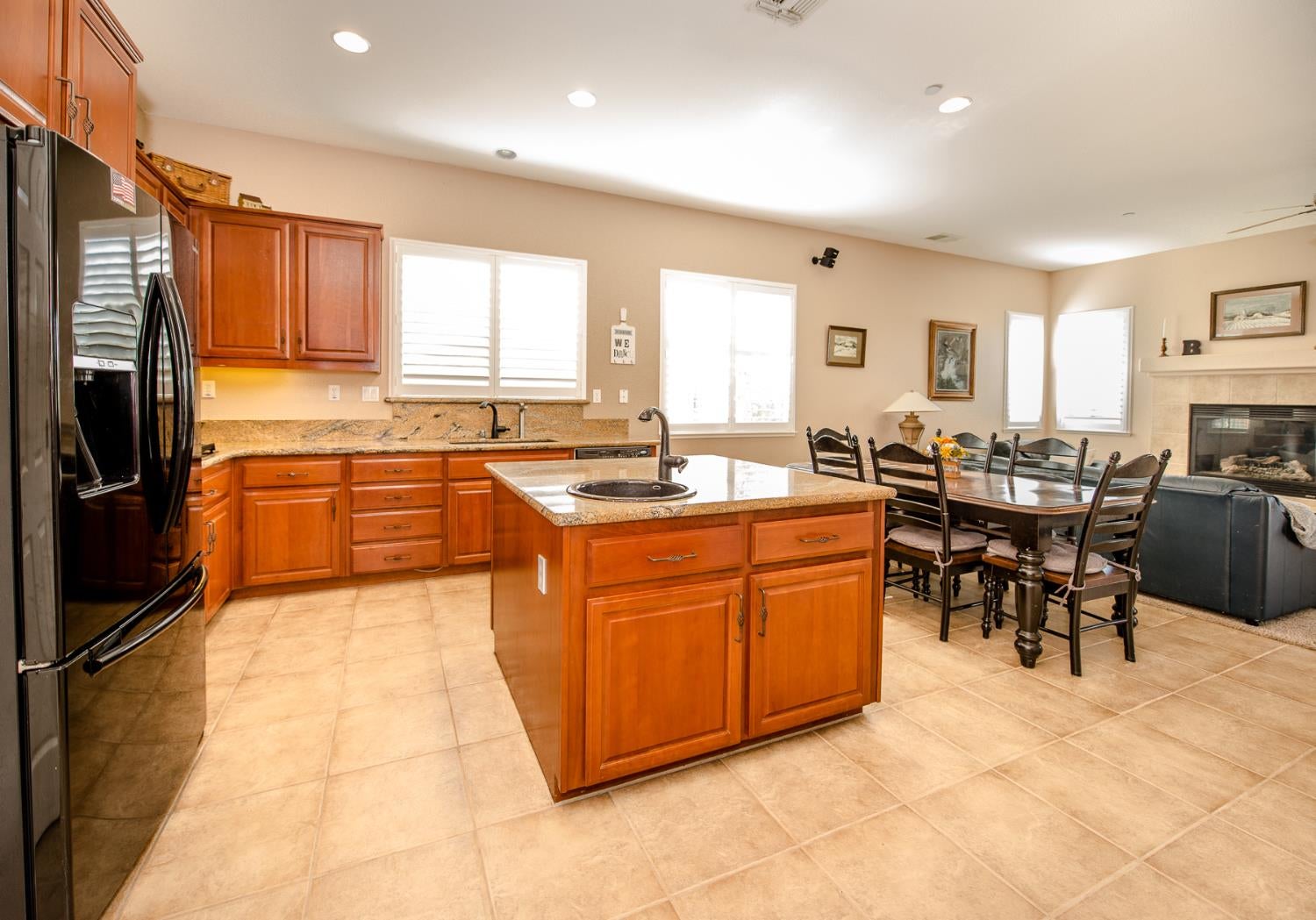 Kitchen with a granite island and warm wood cabinets, open to a dining area and fireplace.