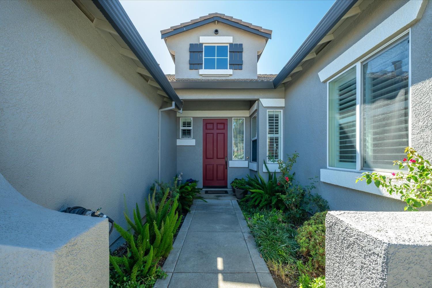 Home entrance with a red front door, covered entry, and landscaped walkway.
