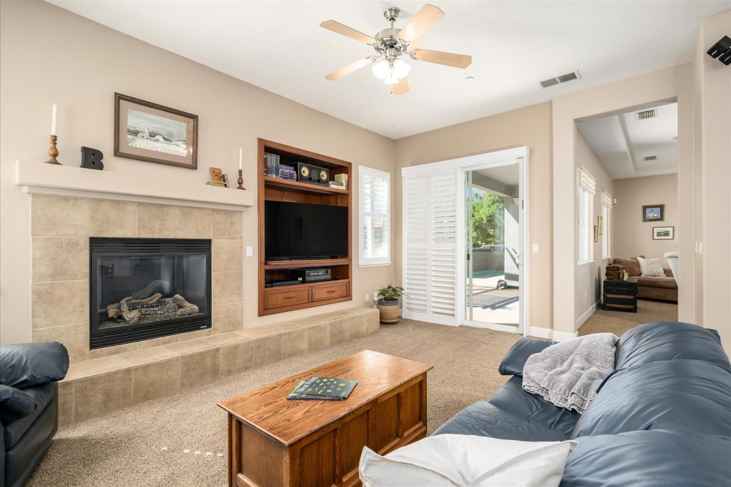 Living room with tiled fireplace, built-in entertainment center, and sliding patio door.