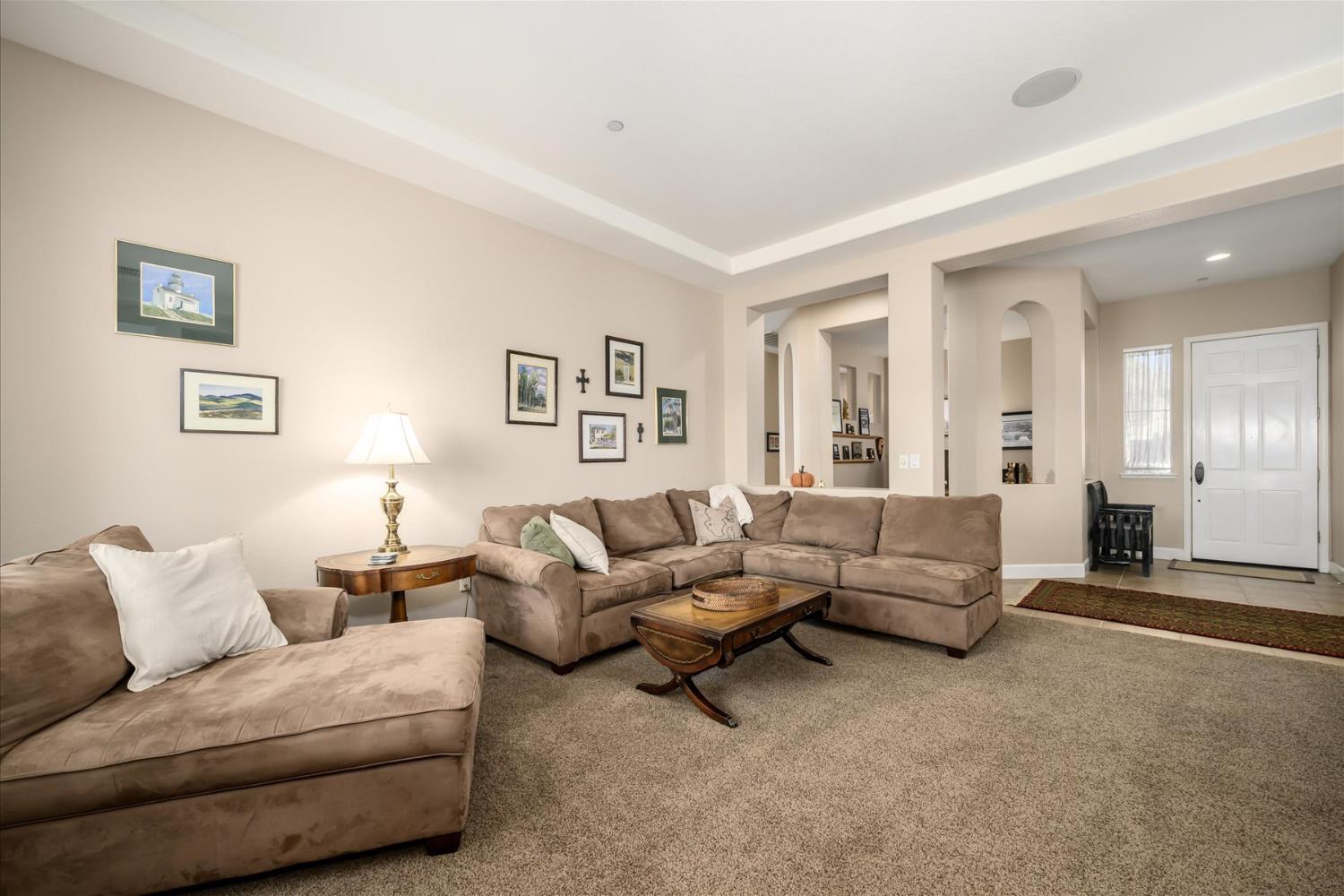 Furnished living room with a taupe sectional and chaise, framed art, and a recessed tray ceiling.