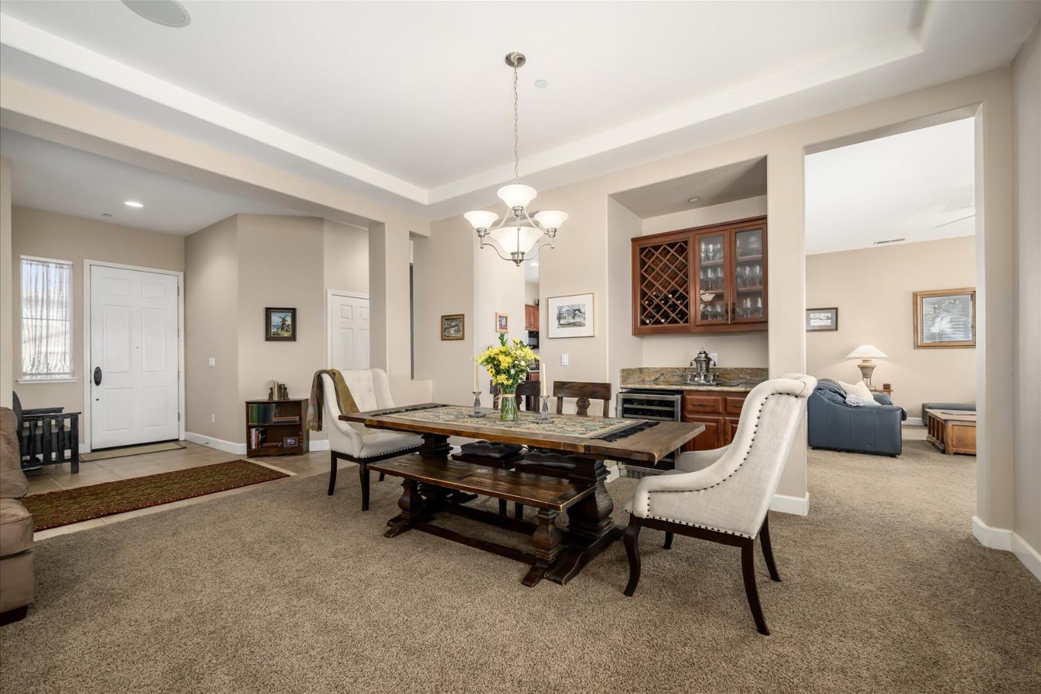 Dining room with a large wooden table, upholstered chairs, and built-in wine cabinet.