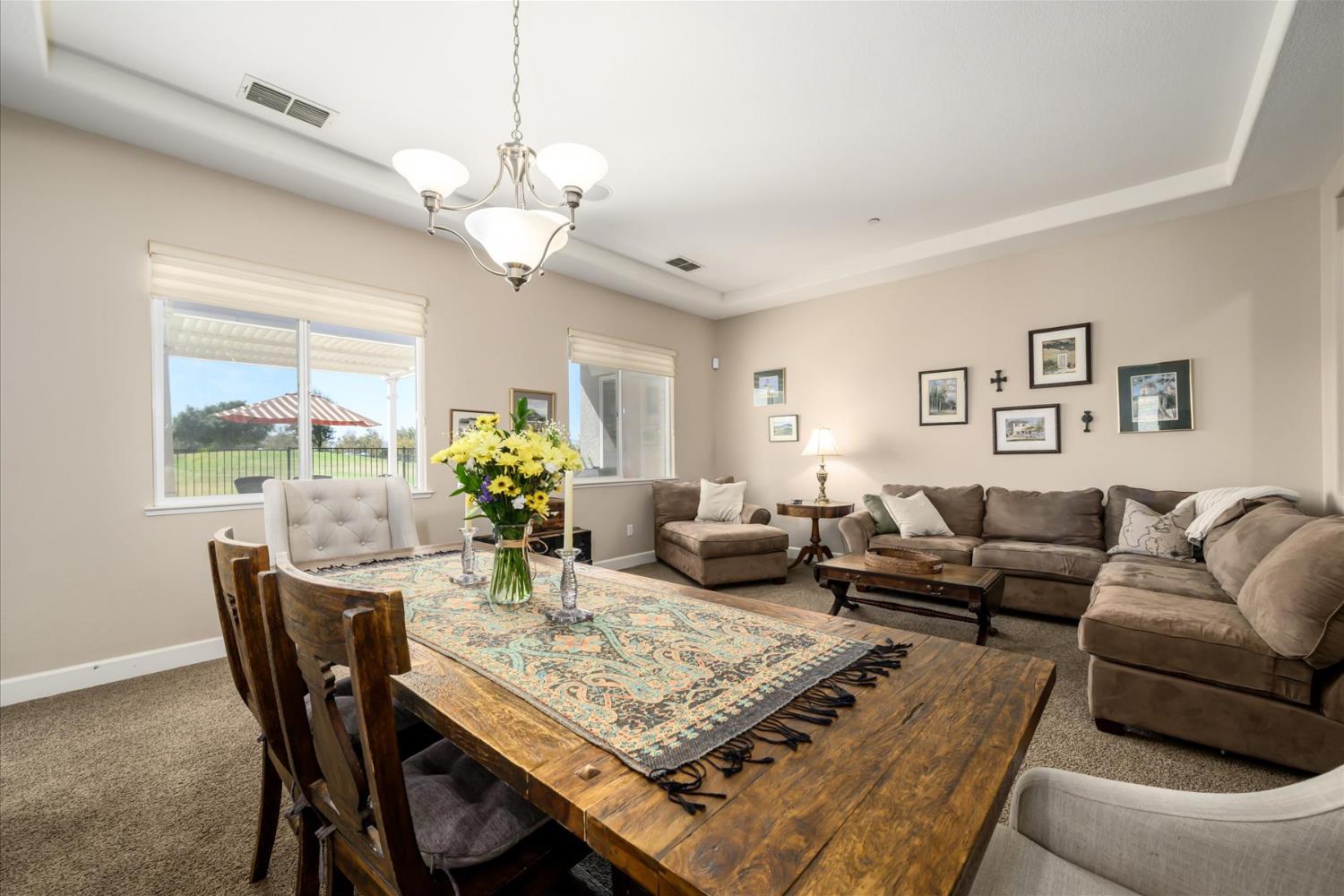 Dining and living area with a rustic wood table, patterned runner, and beige sectional sofa.