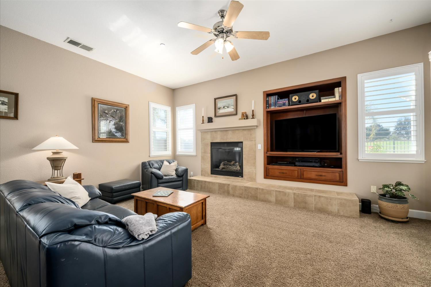 Furnished living room with a tiled fireplace and built-in wooden entertainment center.