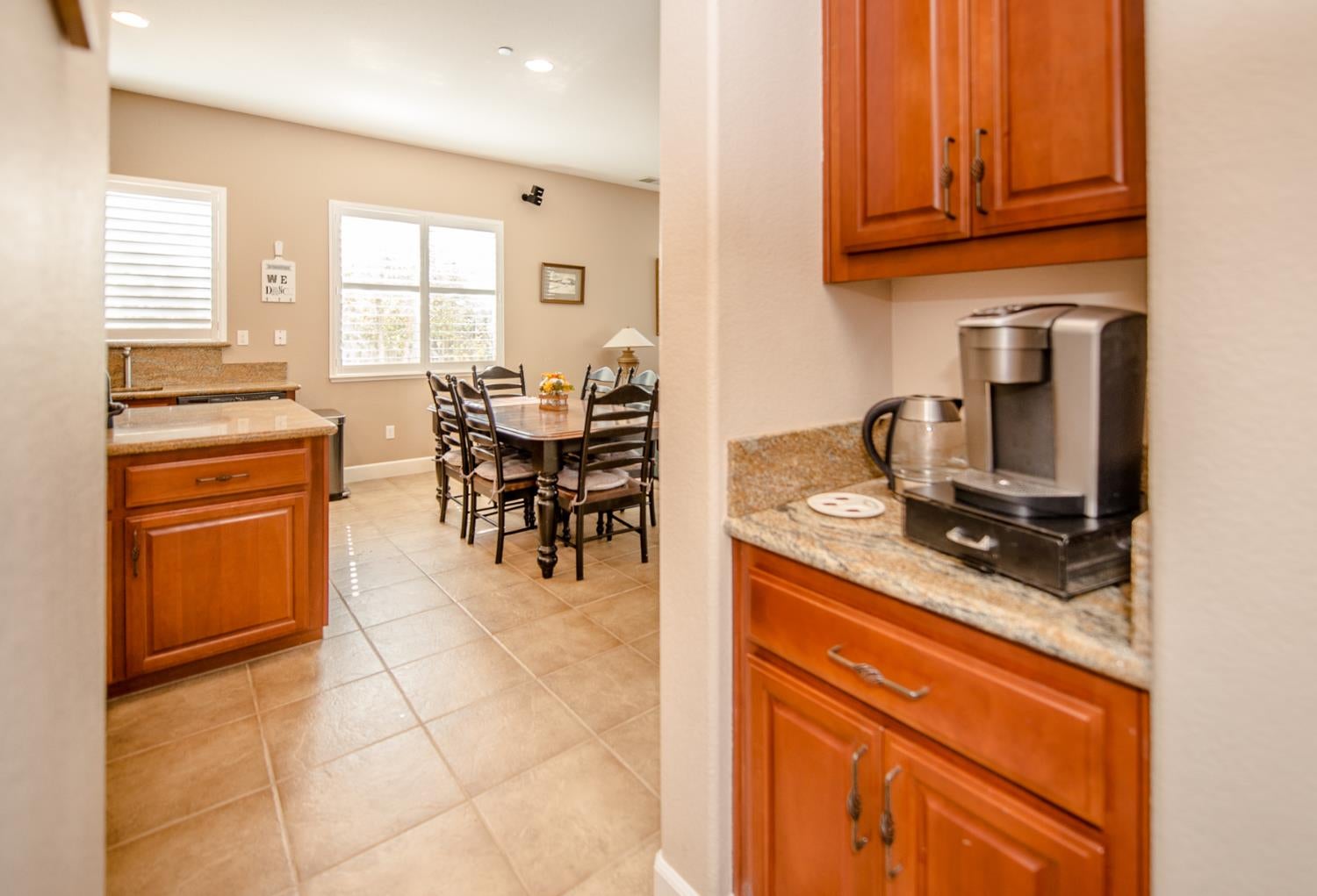 Kitchen and dining area with warm wood cabinets, granite counters, and a dining table by the windows.