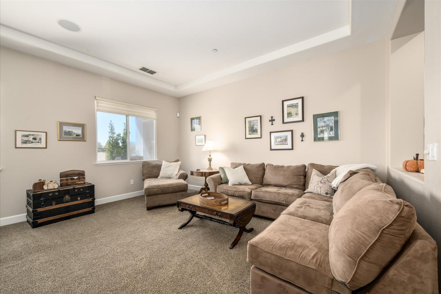 Living room with a beige sectional sofa, matching armchair, and wood coffee table.