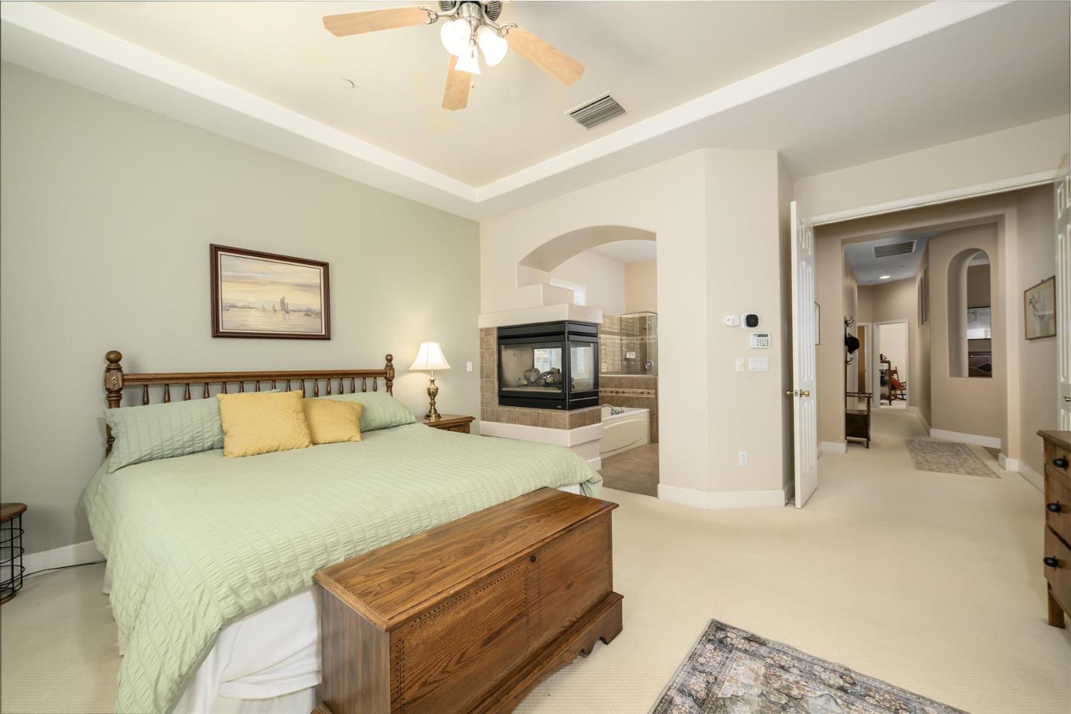 Bedroom with a four-poster bed, corner fireplace, and adjoining bathing area.