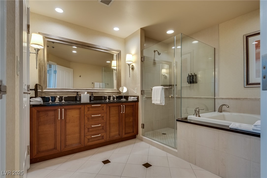 Bathroom with a wood vanity, large mirror, glass shower, and built-in soaking tub.