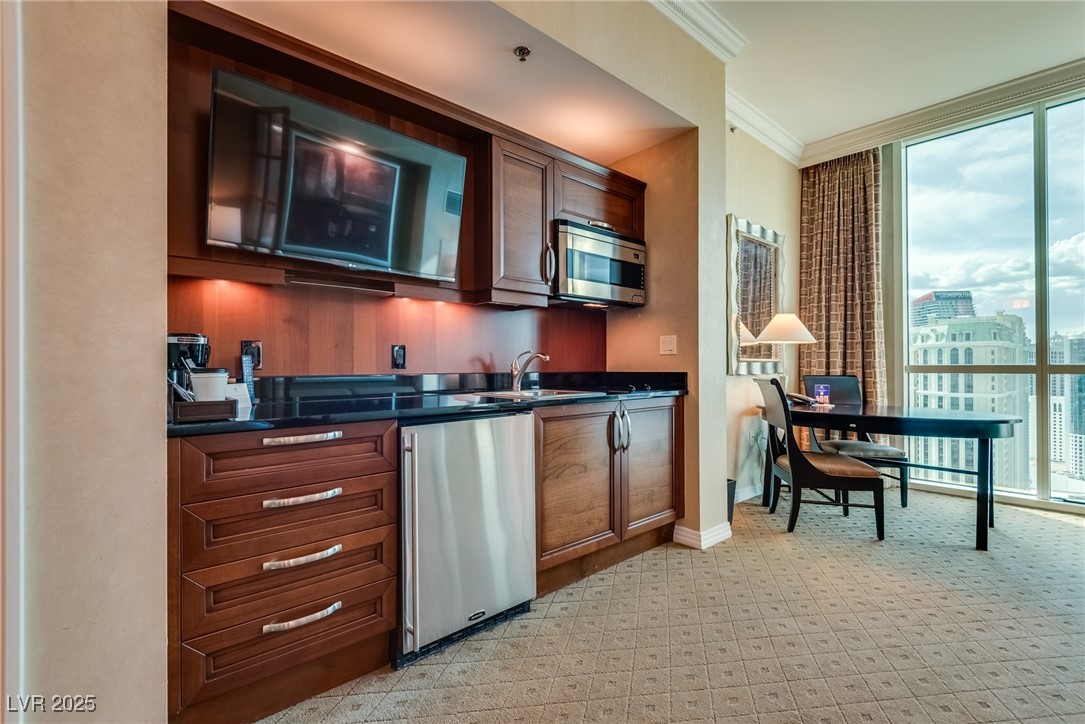 Condo kitchen with dark wood cabinetry and stainless steel appliances beside a dining table overlooking the city.