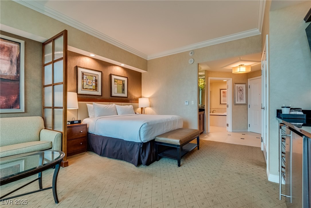 Bedroom with a king bed, pale green sitting area, and open doorway to the bathroom.