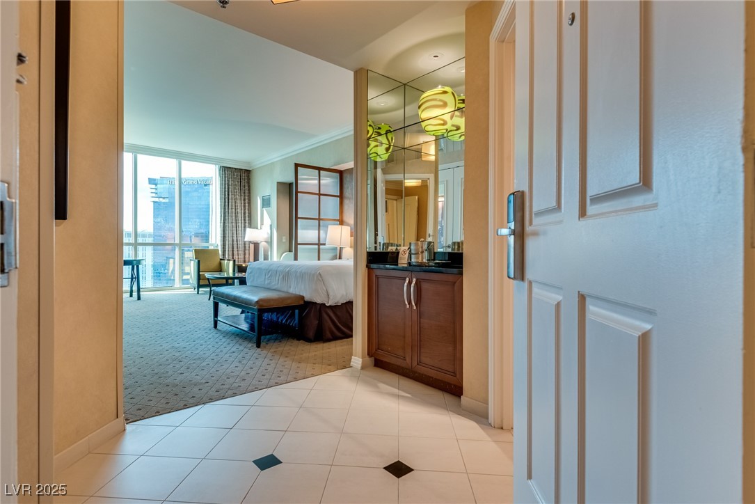 Furnished studio suite with a kitchenette, bed, and large windows overlooking nearby buildings.