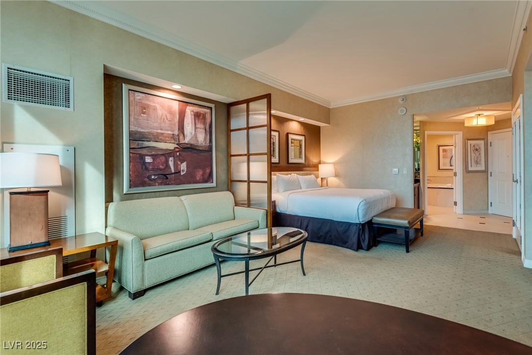 Furnished bedroom suite with a king bed, sofa seating area, and wood-framed divider.