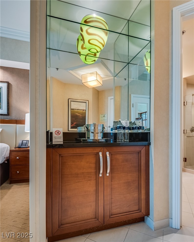 Built-in wet bar with wood cabinets, mirrored backsplash, and bottled water.
