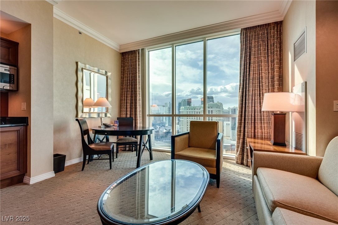 Furnished living room with a dining nook and floor-to-ceiling windows overlooking the city skyline.