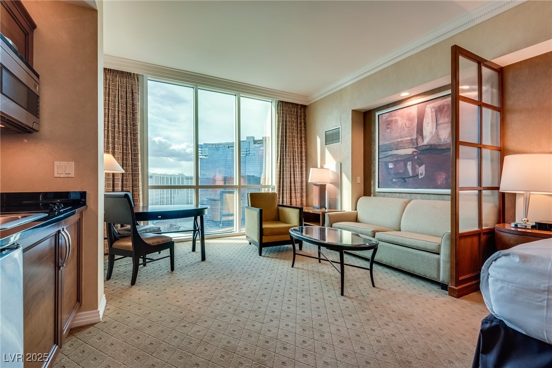 Furnished hotel suite living area with floor-to-ceiling windows overlooking Las Vegas.