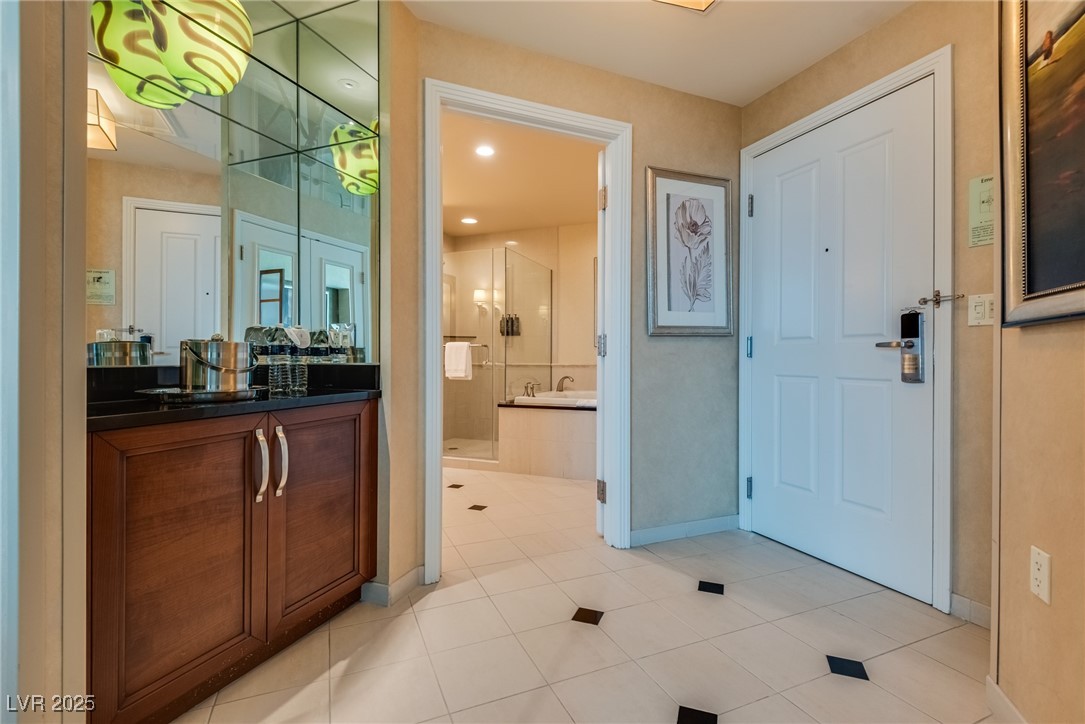 Entry area with a dark wood vanity and mirrored wall beside an open bathroom doorway.