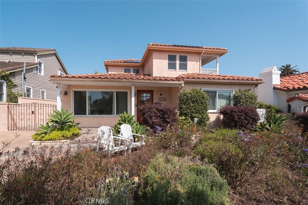 Two-story peach stucco home with a terracotta tile roof and landscaped front yard.