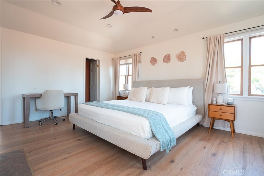 Bright bedroom with a large white bed, pale blue throw, and light wood floors.