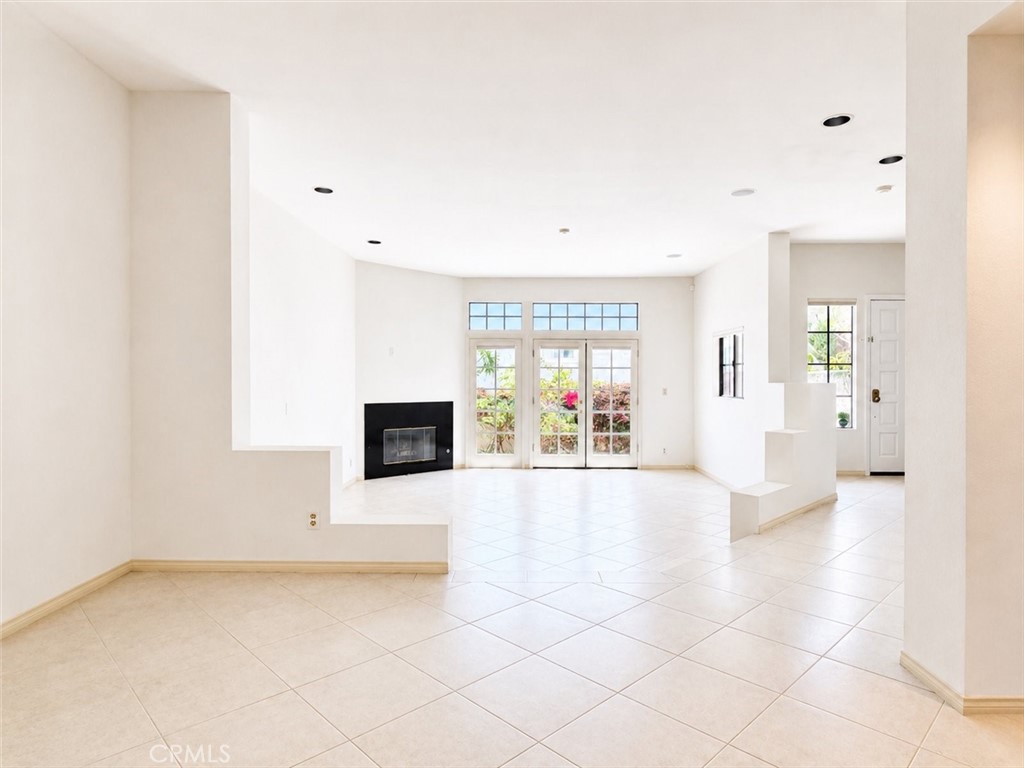 Open living room with tiled floors, a black fireplace, and garden-facing glass doors.