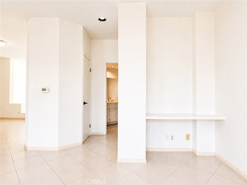 Empty tiled room with a built-in counter ledge and doorway to a bathroom.