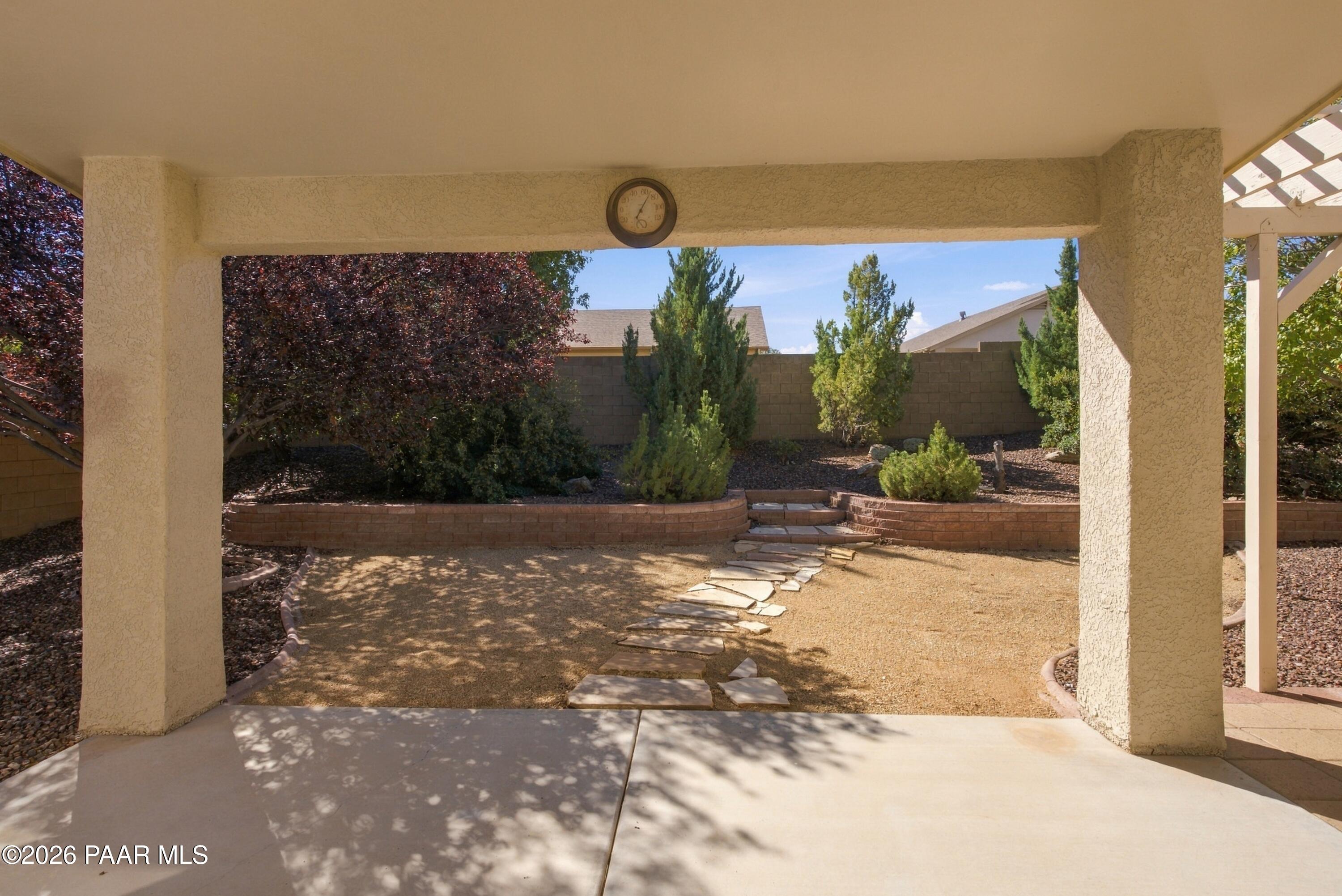 Covered patio overlooking a landscaped yard with raised planting beds and a winding stone path.