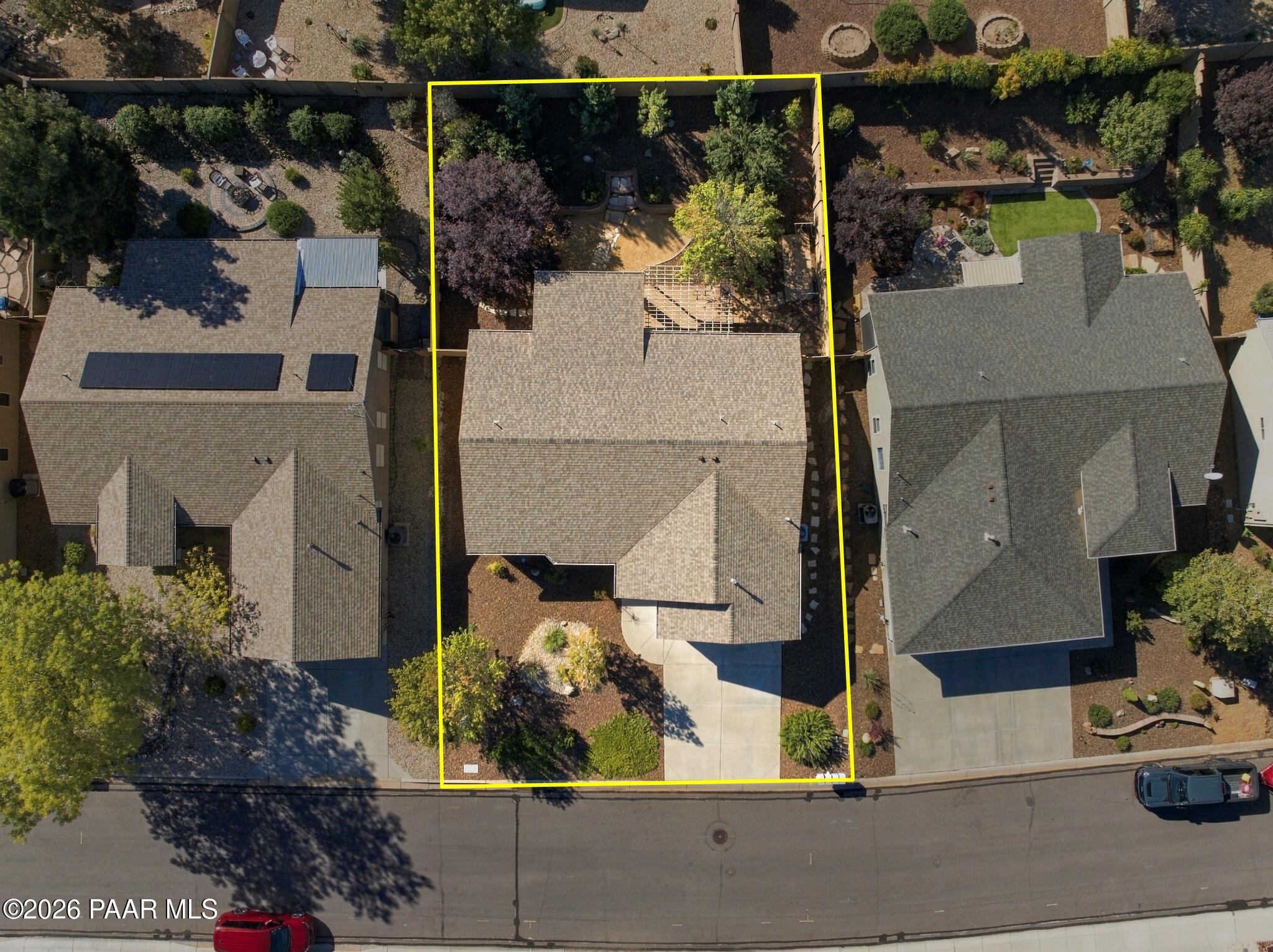 Aerial view of the home and landscaped lot outlined in yellow, with its driveway and backyard patio visible.