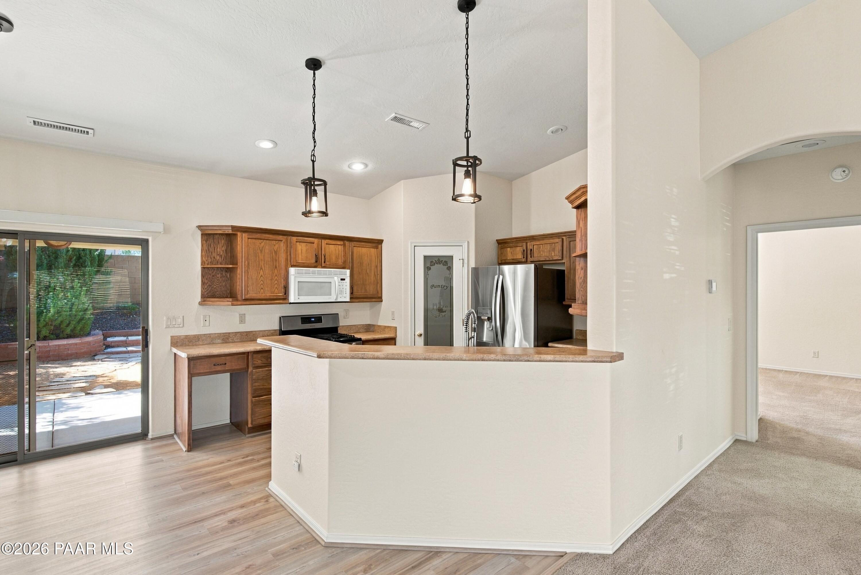 Kitchen with wood cabinets, stainless steel appliances, and a peninsula beside a sliding glass door.