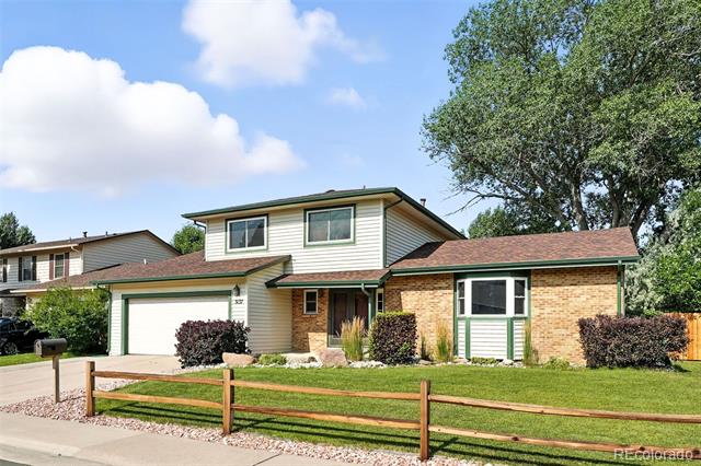 Split-level home with brick and siding, an attached garage, and a fenced front lawn.