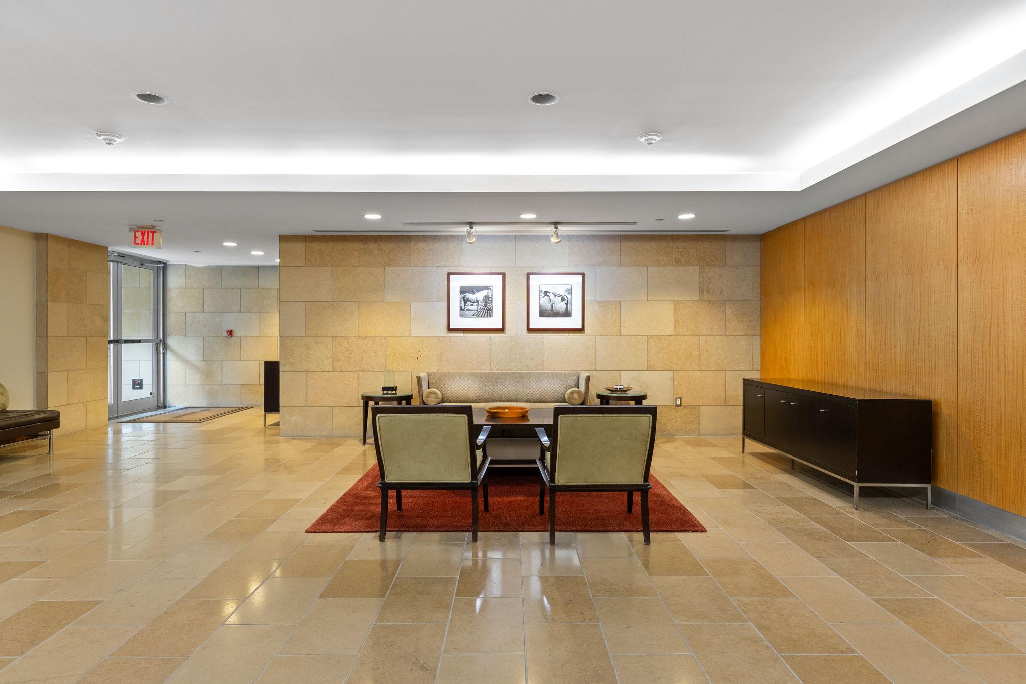 Building lobby with stone walls, wood paneling, and a seating area on a red rug.