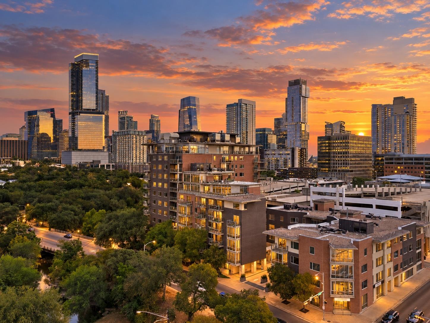 Downtown Austin skyline at sunset above nearby condos and tree-lined streets.