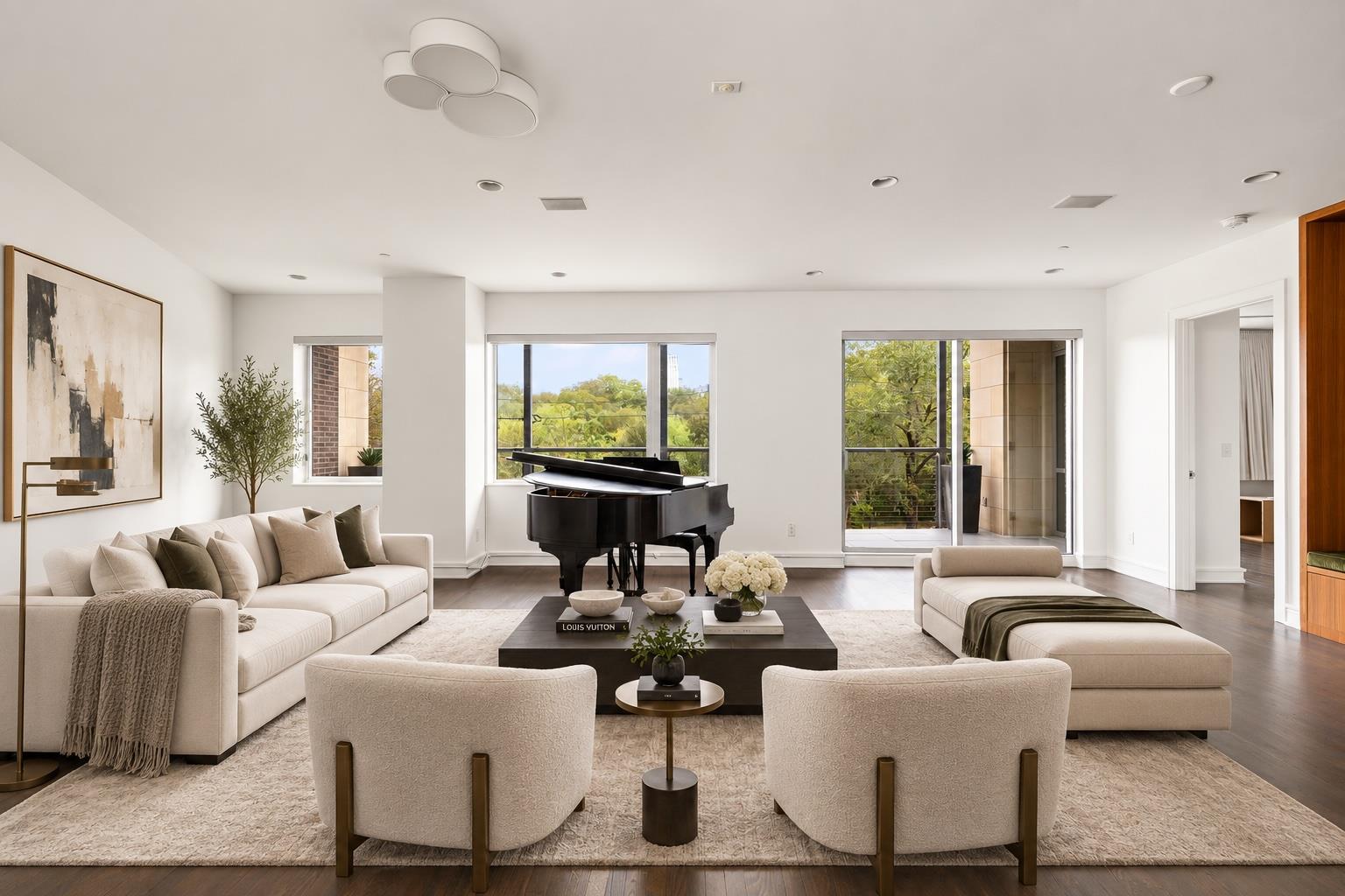 Living room with a black grand piano, cream seating, and large windows overlooking leafy trees.