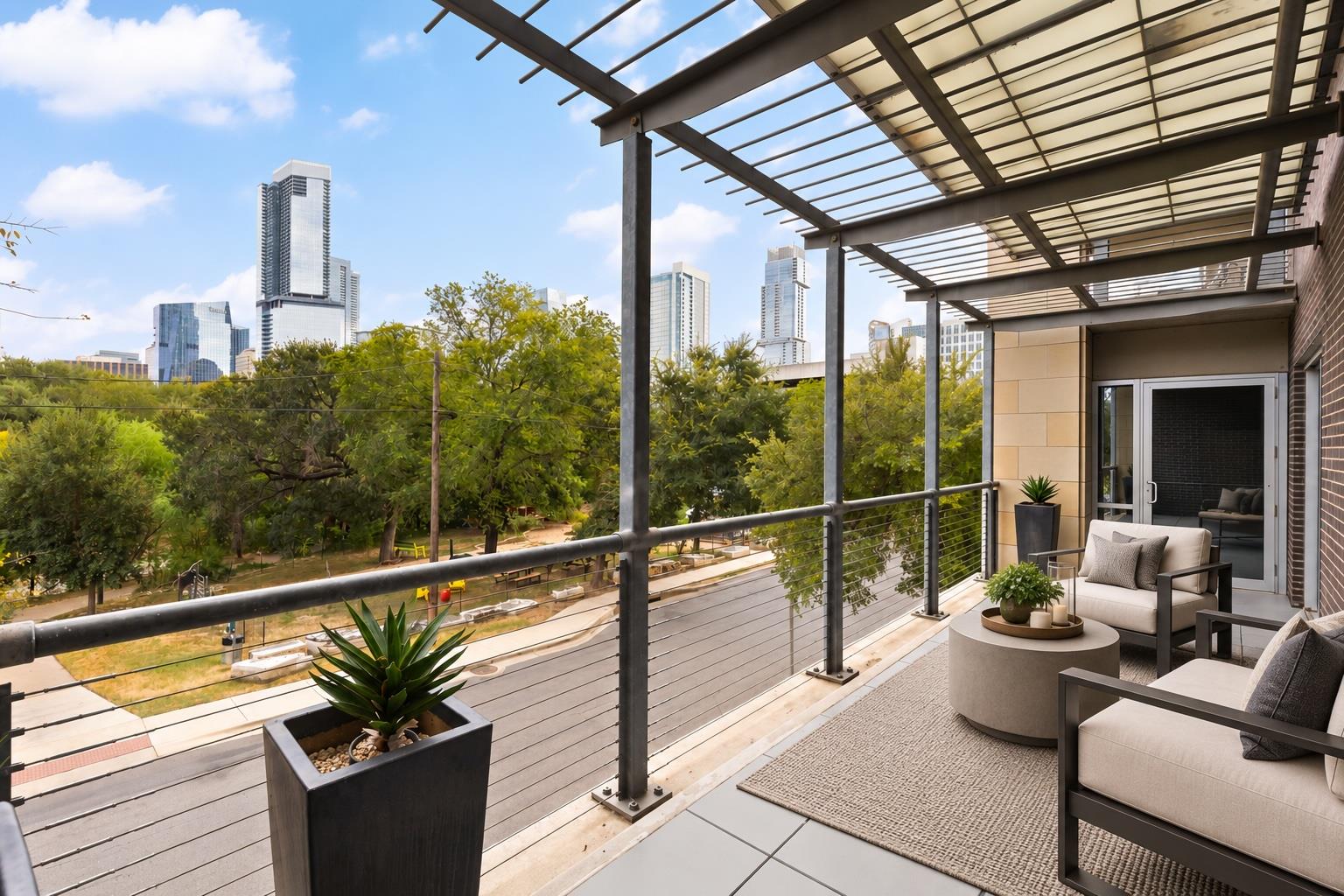 Furnished balcony beneath a pergola, overlooking trees and the Austin downtown skyline.