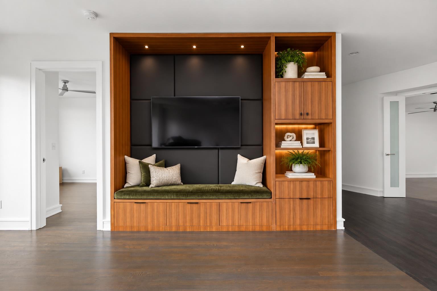 Living room with a walnut built-in media wall, television, and cushioned bench seating.