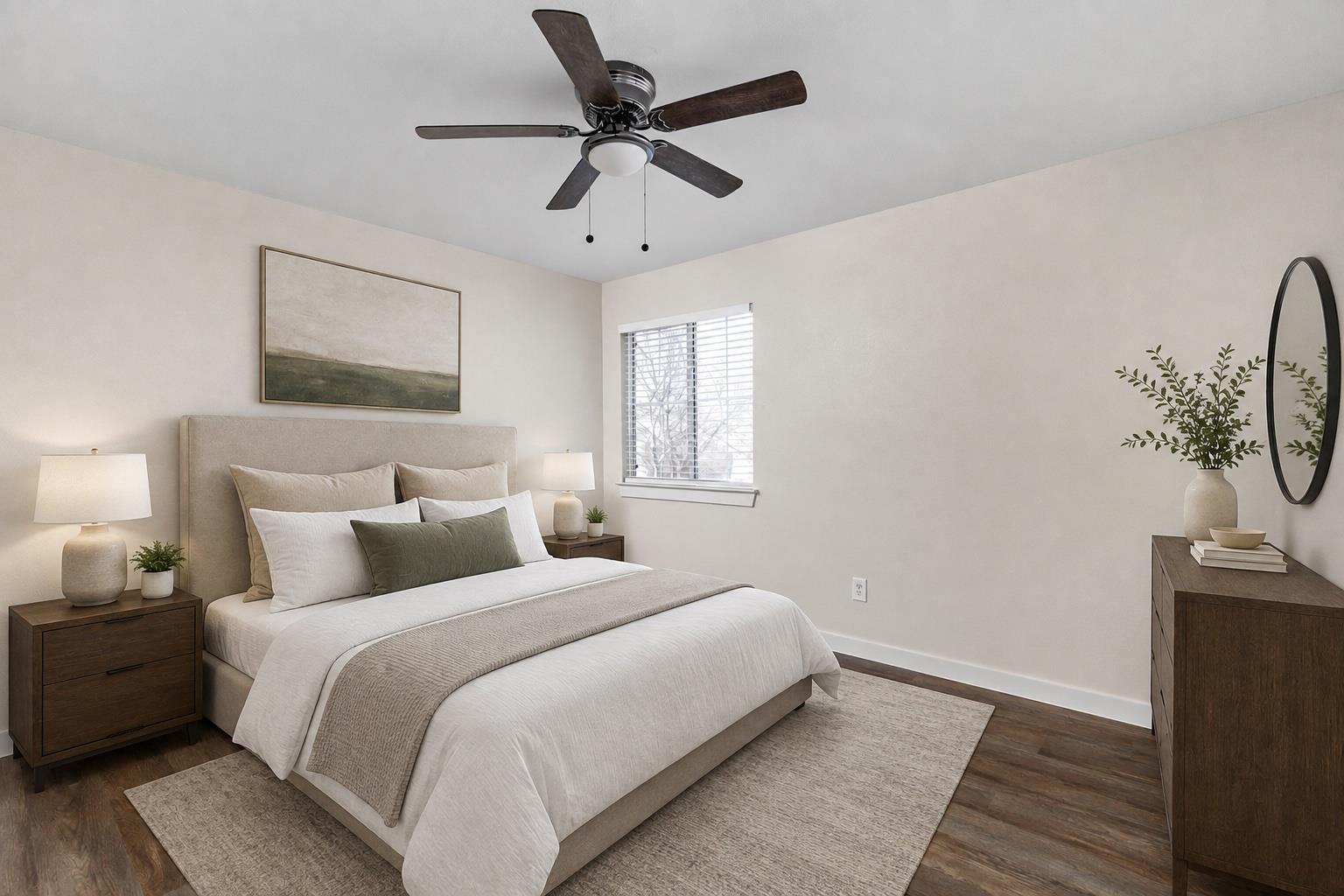 Staged bedroom with a neutral upholstered bed, dark wood furniture, and a ceiling fan.