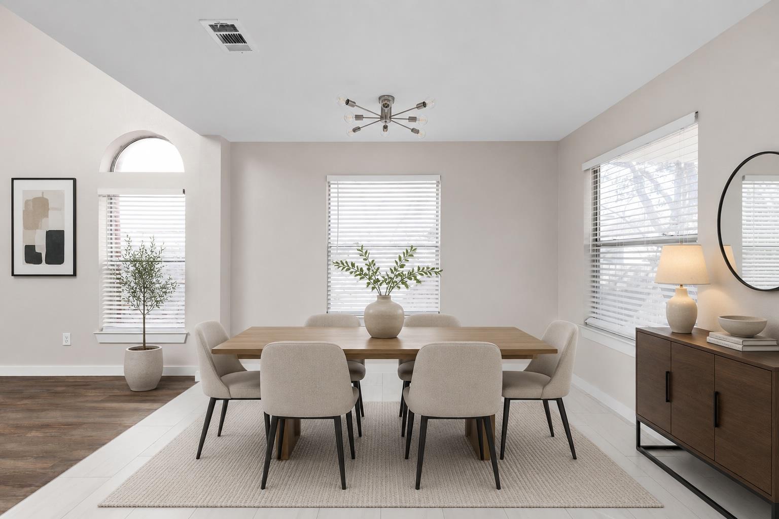 Dining room with a wood table, upholstered chairs, and three windows with blinds.