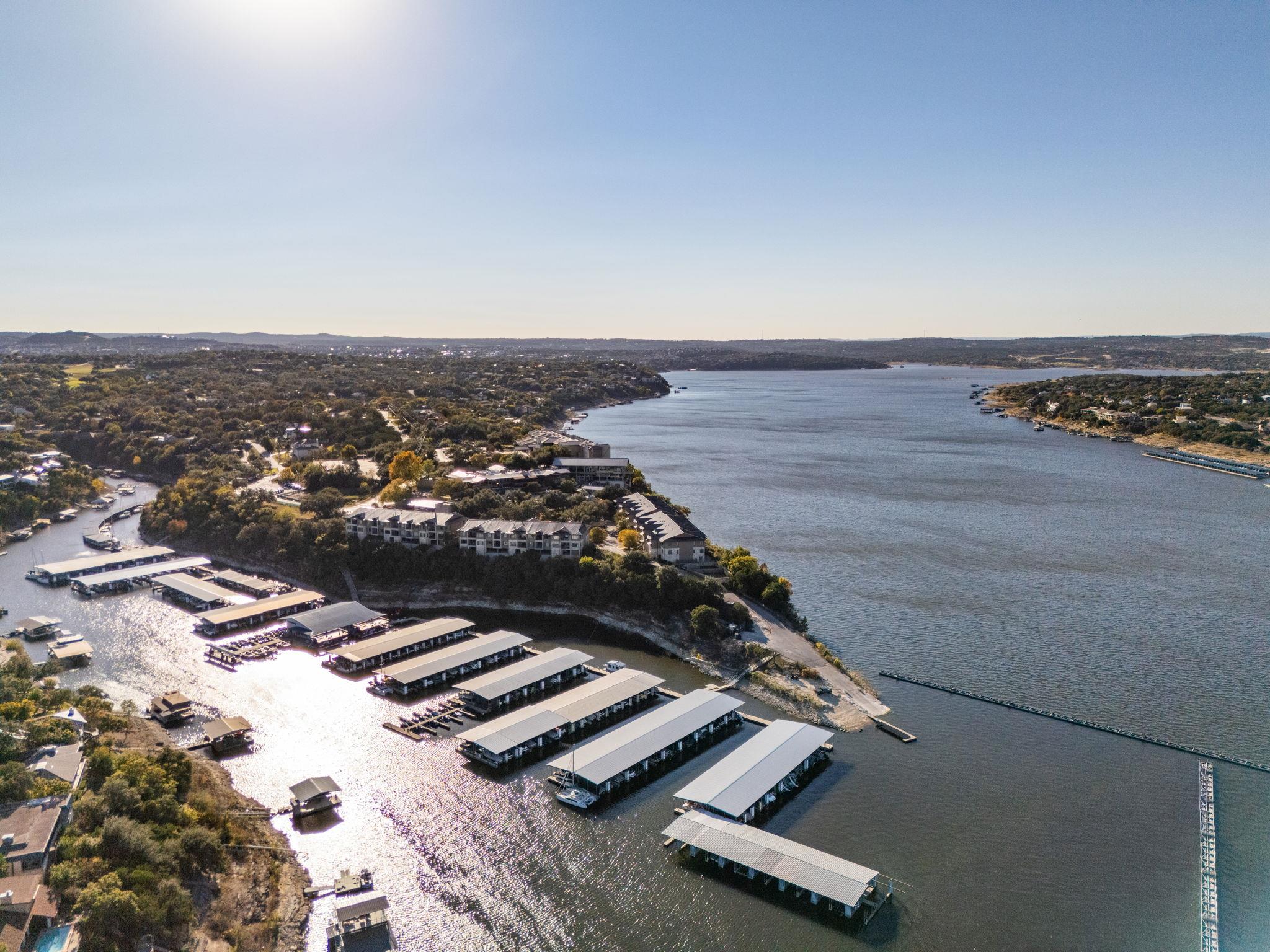 Aerial view of a lakeside marina with rows of covered boat slips along a wooded shoreline.
