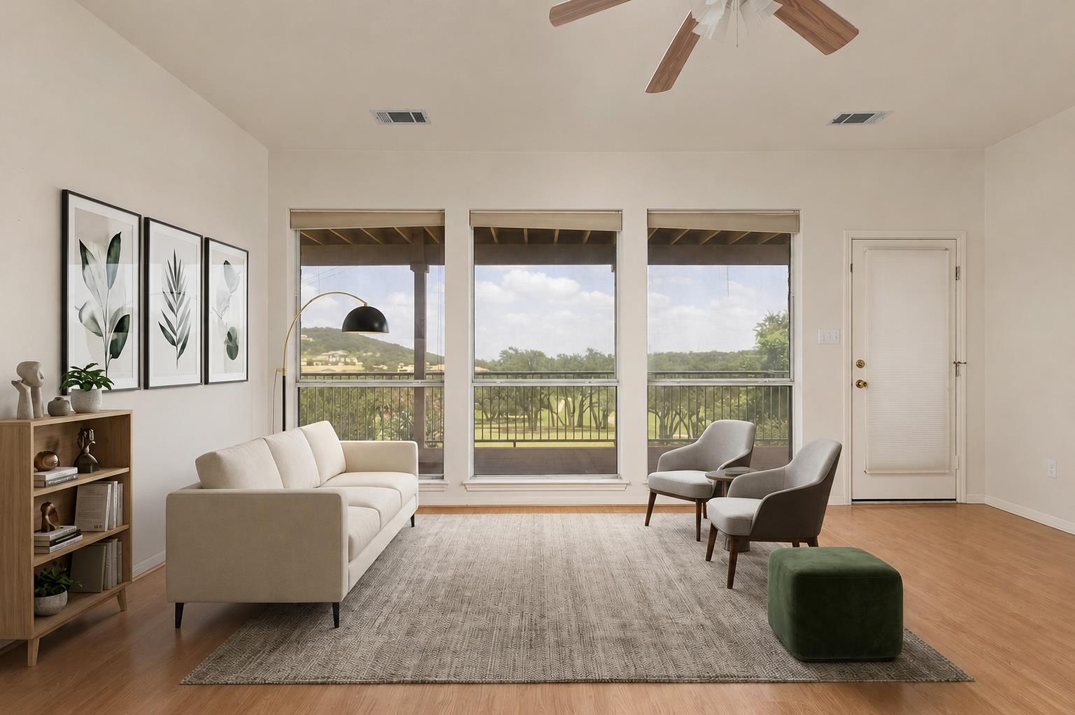 Staged living room with large windows overlooking greenery and distant hills.