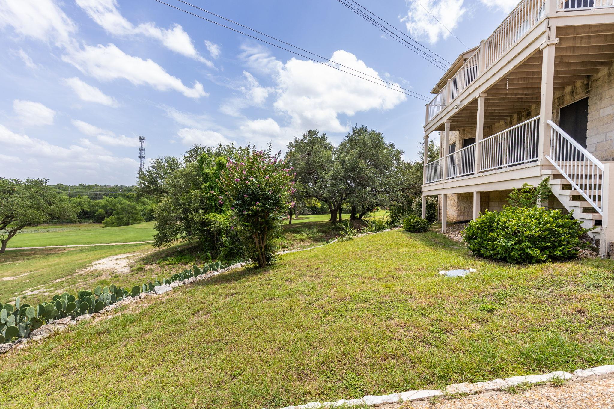 Stone home with raised decks overlooks a grassy yard and golf course.