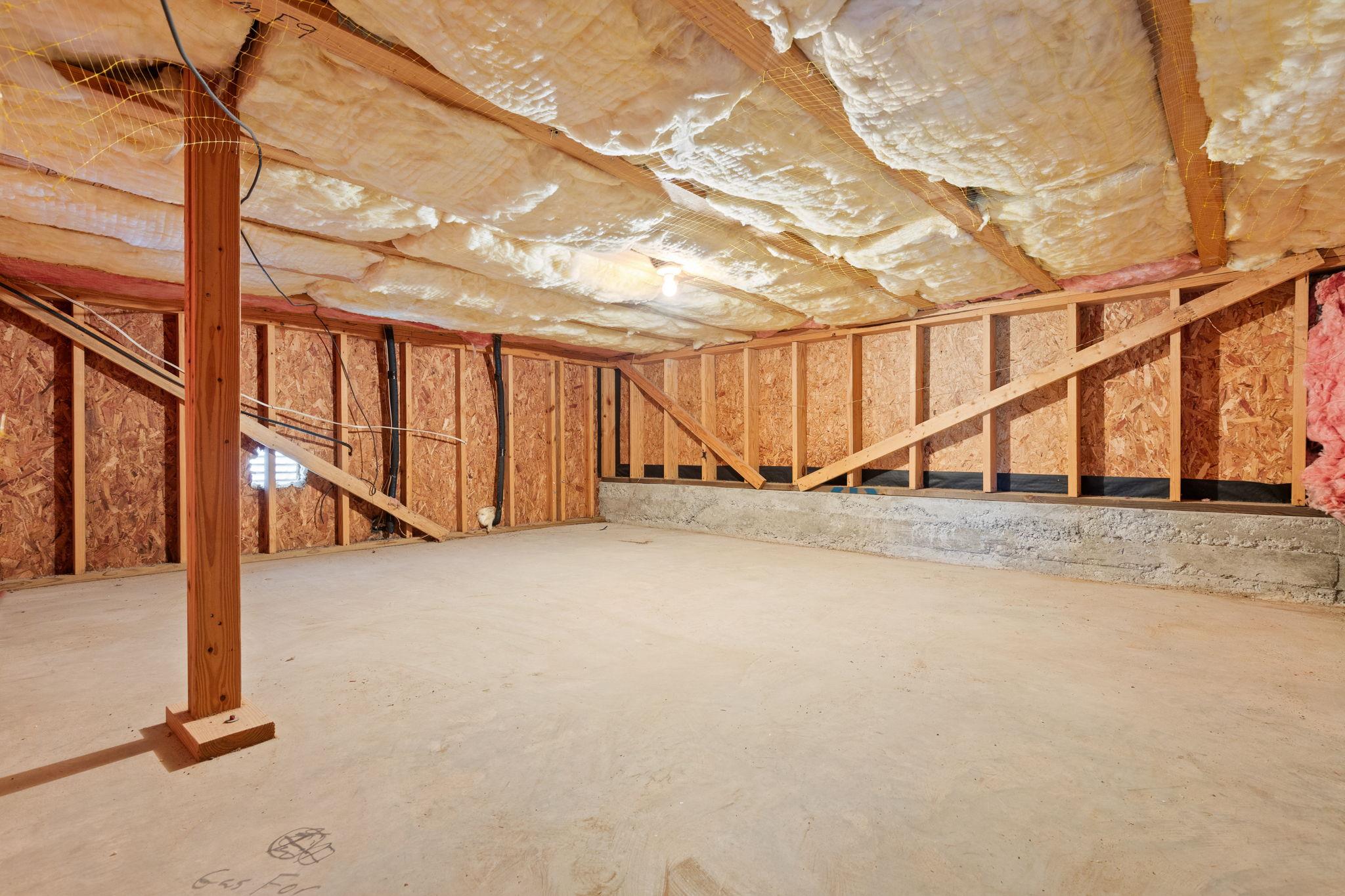 Unfinished basement with exposed framing, insulated ceiling, and bare concrete floor.