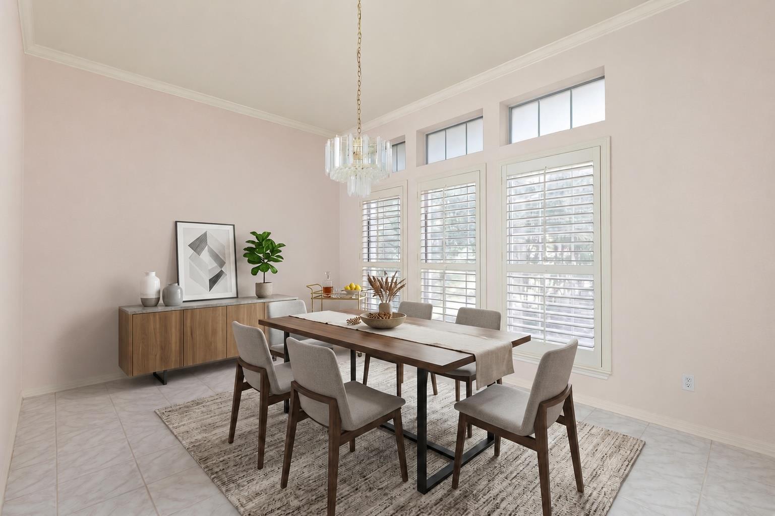 Dining room with a long wooden table, upholstered chairs, tall shuttered windows, and a glass chandelier.