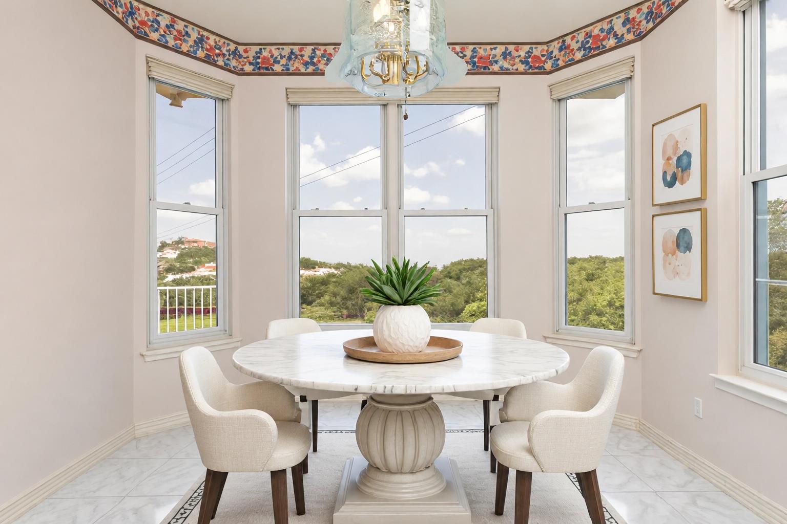 Dining nook with a round marble table and tall windows overlooking wooded hills.