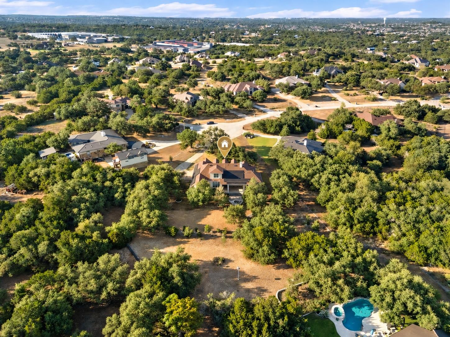 Aerial view of a wooded residential property with a marked home and backyard pool.