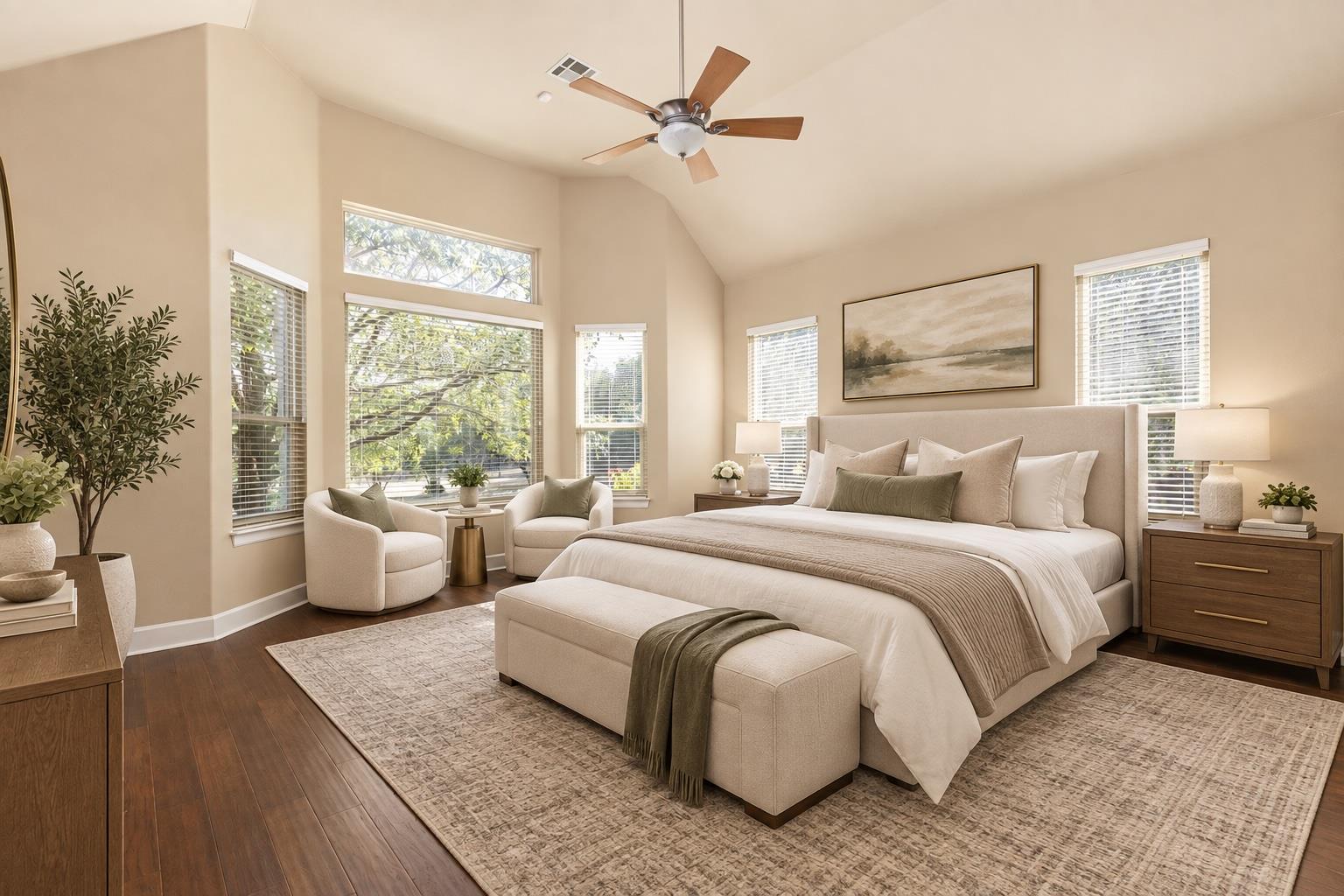 Staged bedroom with a king bed, vaulted ceiling, large windows, and two armchairs.