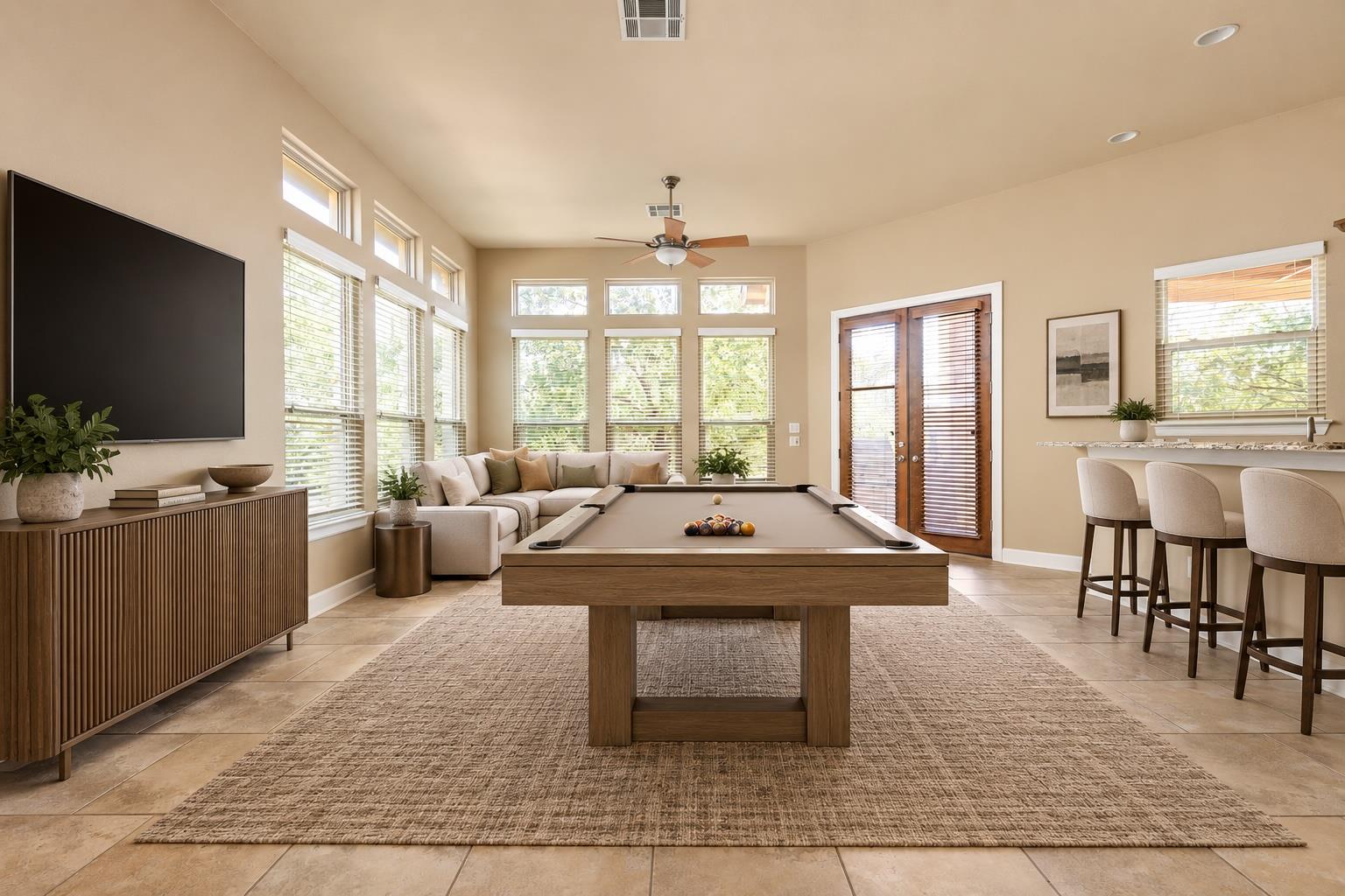 Game room with billiards table, sectional sofa, wall-mounted TV, and bar seating.